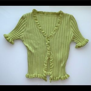 A green ruffle trim top with a few buttons and an open bottom
